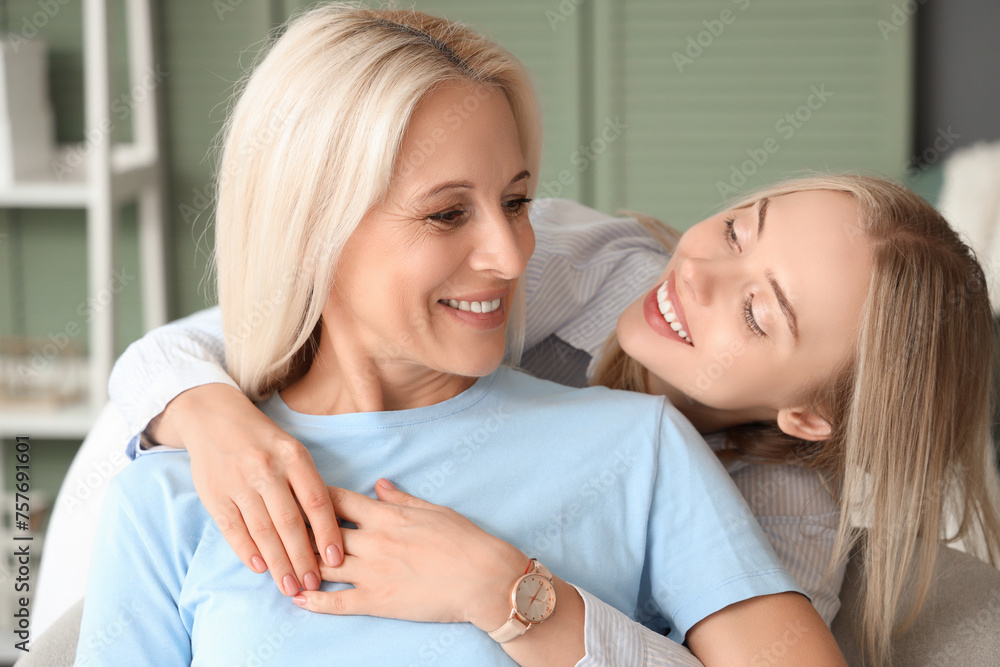 Happy young beautiful woman with her mother hugging in living room