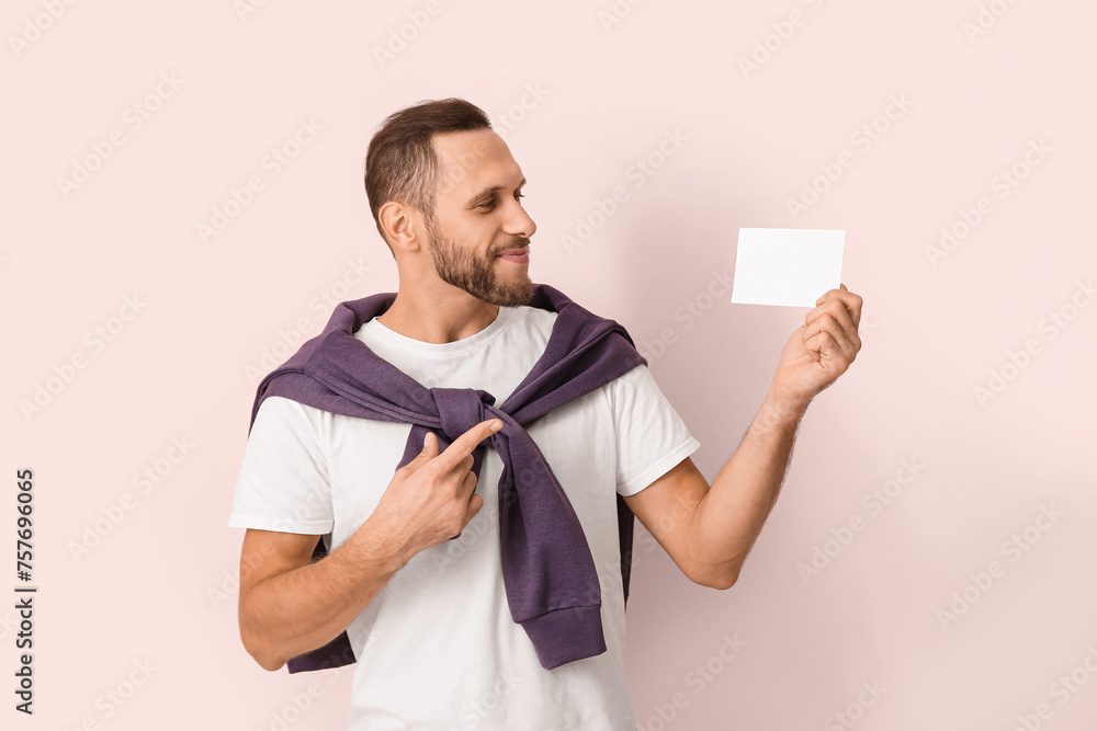 Young man pointing at blank ballot on pink background Young man pointing at blank ballot on pink background