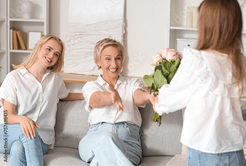 Little girl giving roses to her grandmother and mom at home