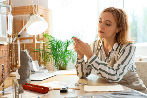 Female jeweler examining ea...