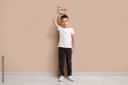 Cute little boy measuring h...