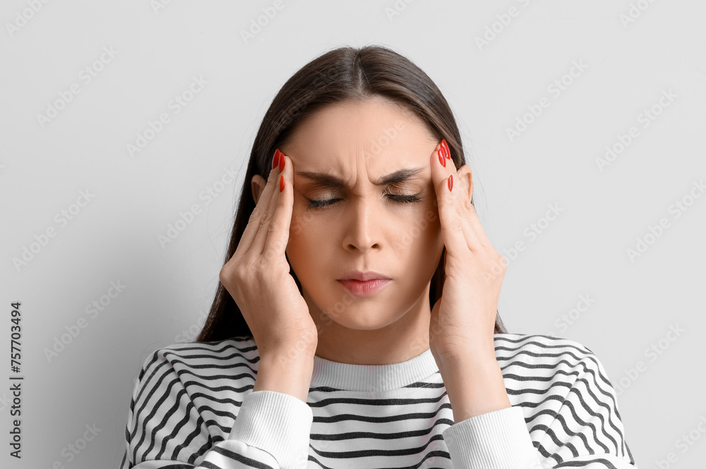Young woman suffering from headache on light background, closeup Young woman suffering from headache on light background, closeup