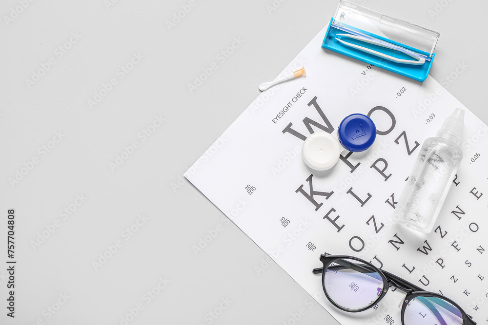 Fototapeta premium Stylish eyeglasses with eye test chart, container and solution for contact lenses on white background