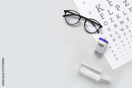 Stylish eyeglasses with eye test chart, container and solution for contact lenses on white background