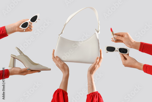 Female hands with stylish women's bag, sunglasses and high heels on grey background