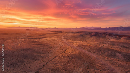 An aerial view of a vast desert at sunset  the landscape bathed in twilight light creating a serene and majestic atmosphere.