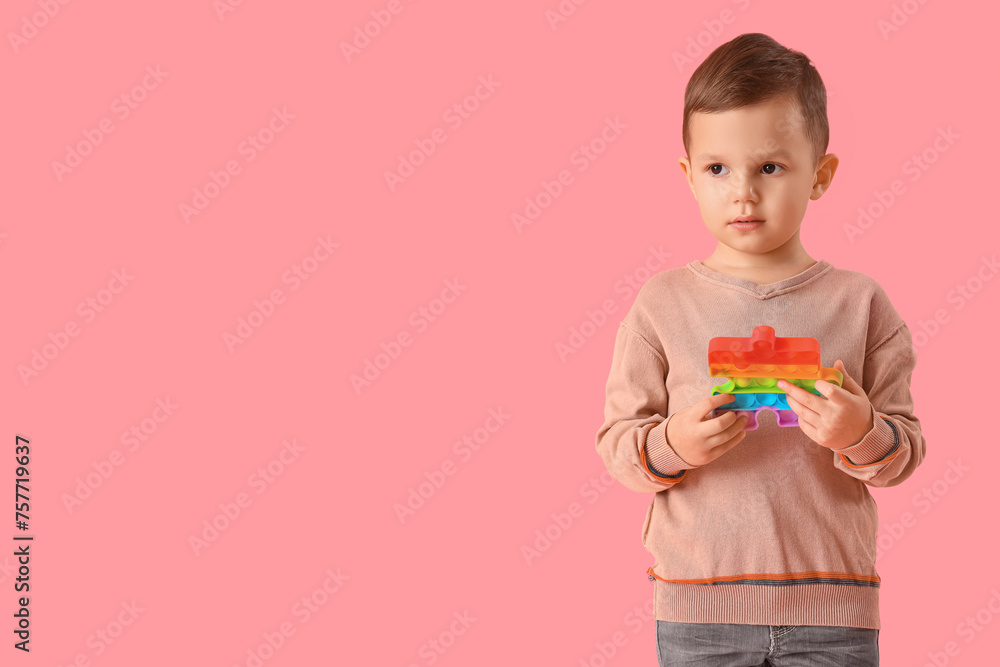 Little boy with autistic disorder and pop it fidget toy on pink background Little boy with autistic disorder and pop it fidget toy on pink background