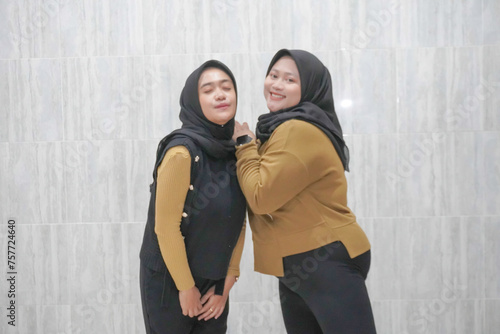 The happy expression of two Asian Indonesian hijab women wearing brown and black clothes
