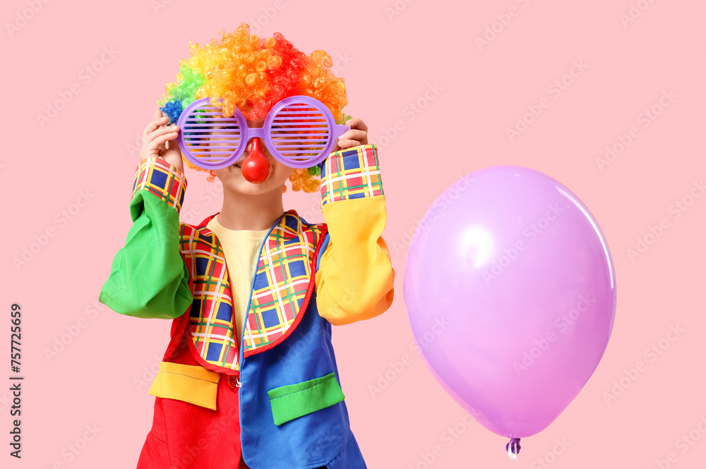 Cute little boy in clown costume with funny glasses and balloon on pink background. April Fools Day celebration Cute little boy in clown costume with funny glasses and balloon on pink background. April Fools Day celebration