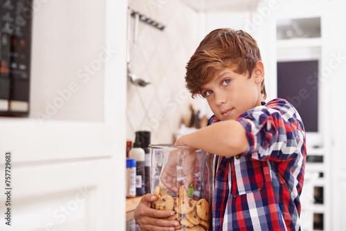 Eating, cookies and portrait of child in home with glass, container or sneaking with a jar of sweets. House, kitchen and kid craving a taste of sugar with biscuit addiction or snack on unhealthy food