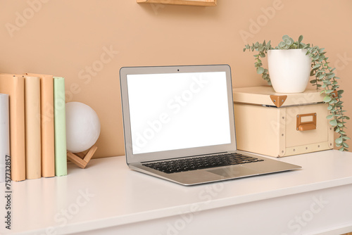 Wallpaper Mural Stylish workplace with houseplant, books and laptop near beige wall Torontodigital.ca