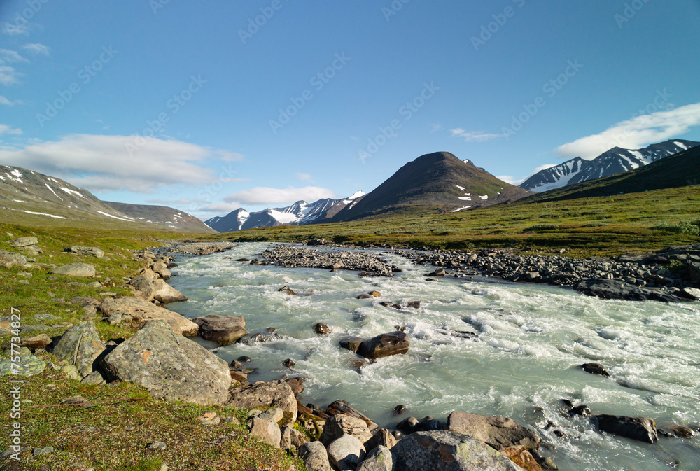 A wild, turbulent mountain river in the Sarek National Park, Sweden. A summer scenery with water in Northern Europe.