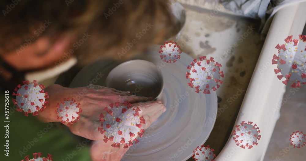 Composite image of covid-19 cells floating against close up of hands working on pottery wheel