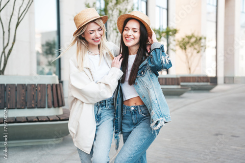 Two young beautiful smiling hipster female in trendy summer clothes. Carefree women posing in the street. Positive models having fun outdoors at sunny day. Cheerful and happy. In hat