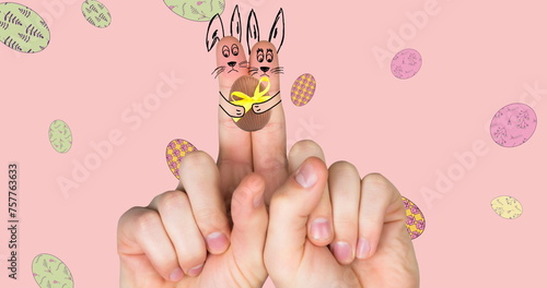 Image of hand with easter decorations and easter eggs over pink background