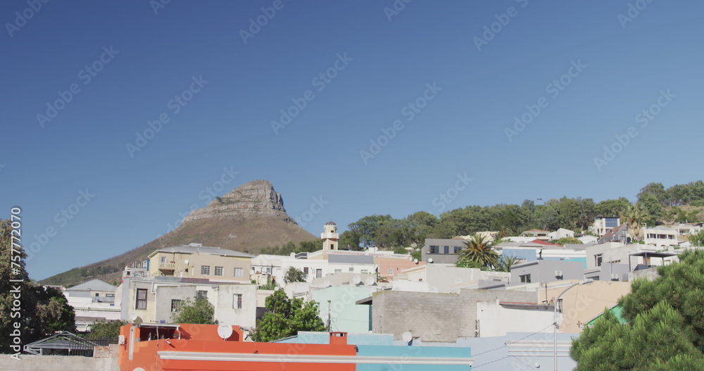 Fototapeta premium General view of cityscape with houses, mountain, trees and blue sky