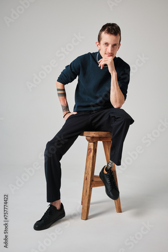 Studio portrait of a successful happy tattooed one legged disabled young male amputee with prosthetic leg wearing casual dark blue clothing. 