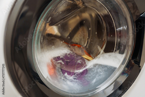 Closeup of washing machine door with spinning laundry photo