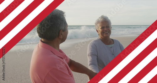 Image of flag of united states of america over senior biracial couple dancing on beach