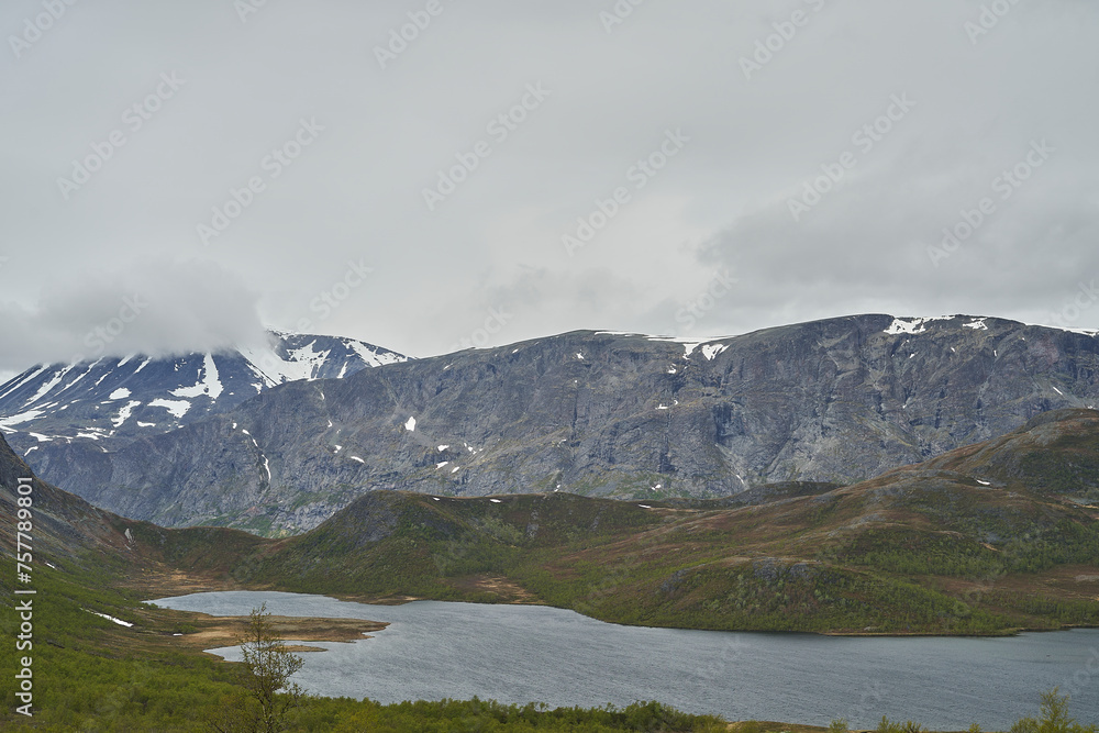 lake in the mountainous landscape of Jotunheimen in Norway, with snow covered peaks in the background, a popular travel destination for hiking. lake in the mountainous landscape of Jotunheimen in Norway, with snow covered peaks in the background, a popular travel destination for hiking.