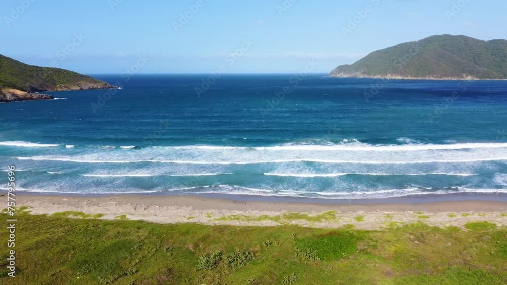 A vibrant beach with waves crashing, surrounded by greenery and hills, under a clear sky, aerial view A vibrant beach with waves crashing, surrounded by greenery and hills, under a clear sky, aerial view