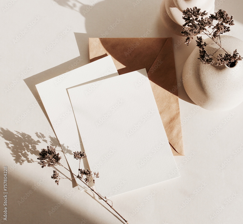 Greeting Cards mockup, empty white blanks, envelope dry flower in a vase, sunlight shadow top view on beige background with copy space. flat lay. Empty white Blank, card template, invitation. - obrazy, fototapety, plakaty 