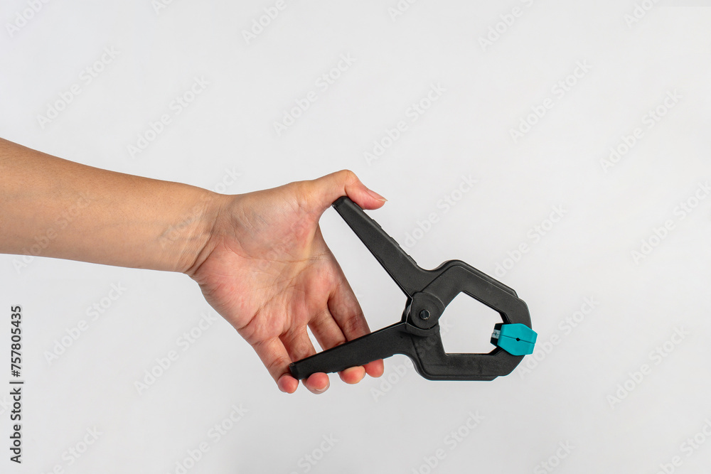 Black plastic spring clamp in hand isolated on white background Black plastic spring clamp in hand isolated on white background
