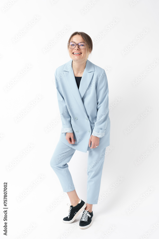 Cheerful young businesswoman in light blue suit and glasses laughing on white background.
