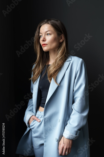 Portrait of a young woman with a confident gaze, wearing a blue blazer.