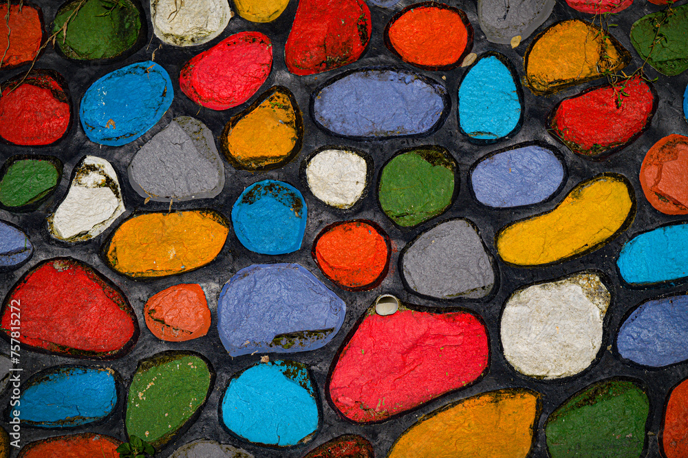 the background of a stone wall that is painted colorfully on each stone pattern