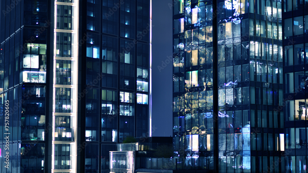 Obraz premium Office building at night, building facade with glass and lights. View with illuminated modern skyscraper.