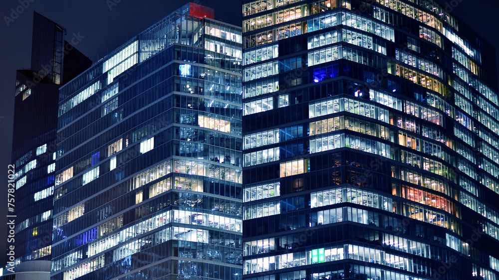 Fototapeta premium Office building at night, building facade with glass and lights. View with illuminated modern skyscraper.
