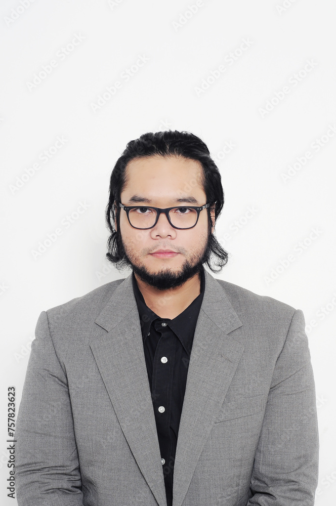 Medium closeup portrait of an Asian man wearing glasses, neatly dressed in a black shirt, jacket and tie on a white background Medium closeup portrait of an Asian man wearing glasses, neatly dressed in a black shirt, jacket and tie on a white background