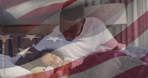 Image of flag of usa waving over african american father reading book to daughter