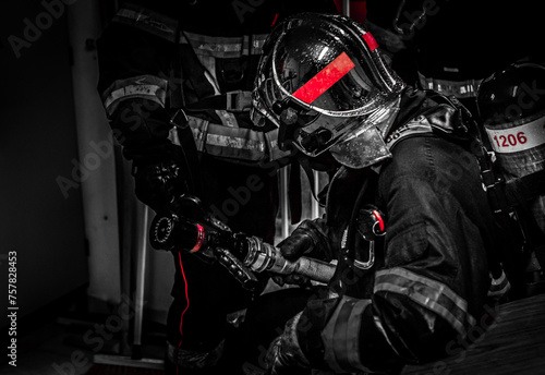 European firefighters in full exercise in a narrow and smoky environment, predominant red color photo