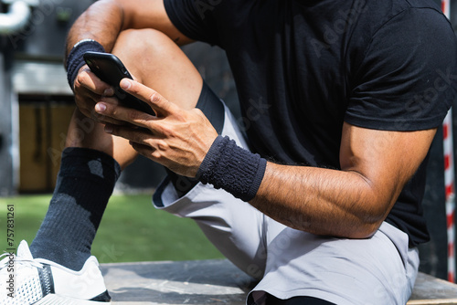 Young Athlete Man Using Smartphone In Gym