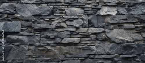 A close up of a grey stone wall made up of various rocks, showcasing the intricate brickwork and composite materials used as building material