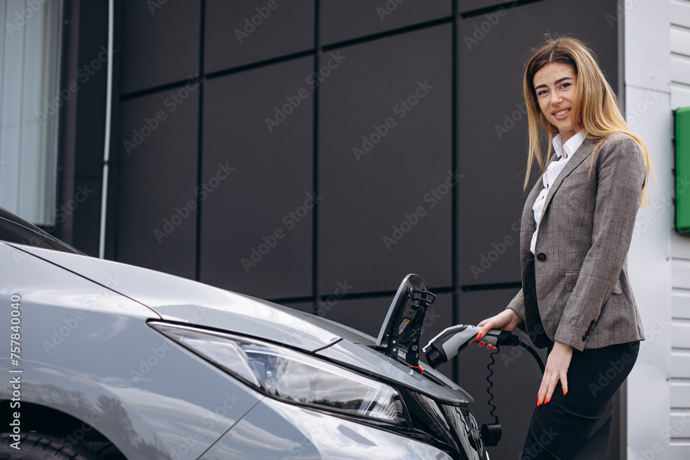 Business woman charging electric car at charging station