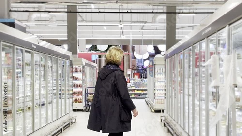 Wallpaper Mural  Man choosing frozen food from a supermarket freezer., reading product information Torontodigital.ca