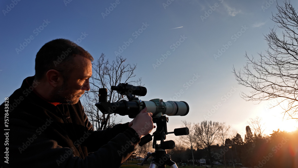 Amateur astronomer observing Sun eclipse and Sun with a telescope and special solar filter.