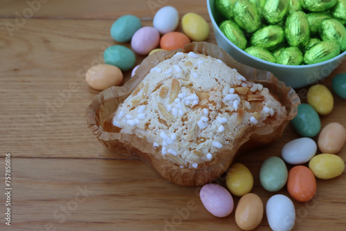 Sweet Easter cake named Colomba Pasquale with colorful chocolate eggs. Italian traditional pastry on wooden table
