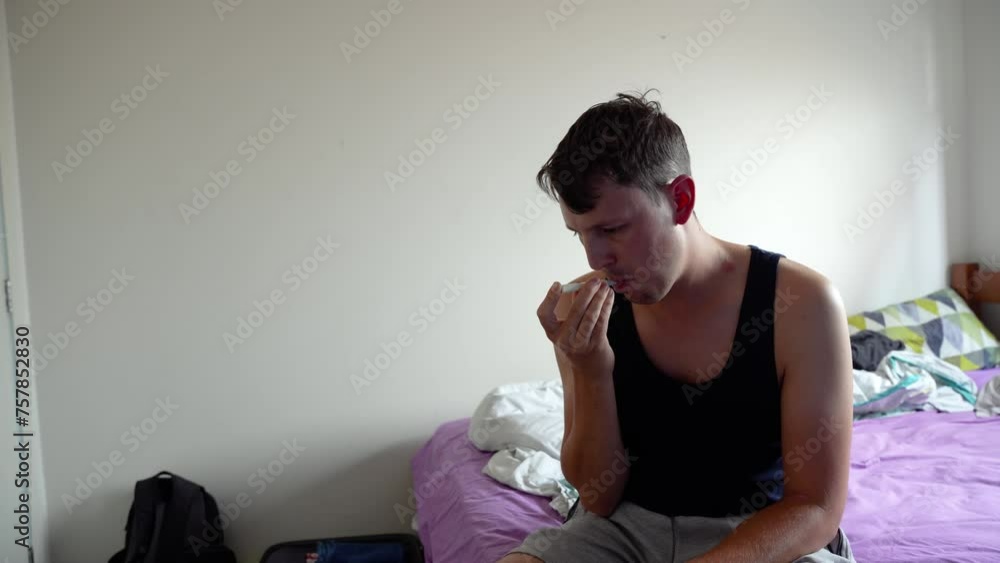 A sick man measuring his fever temperature in the hotel room on vacation. A sick man measuring his fever temperature in the hotel room on vacation.