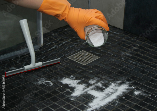 Close up of woman's hands pouring baking soda on shower floor to clean, eco friendly cleaning 