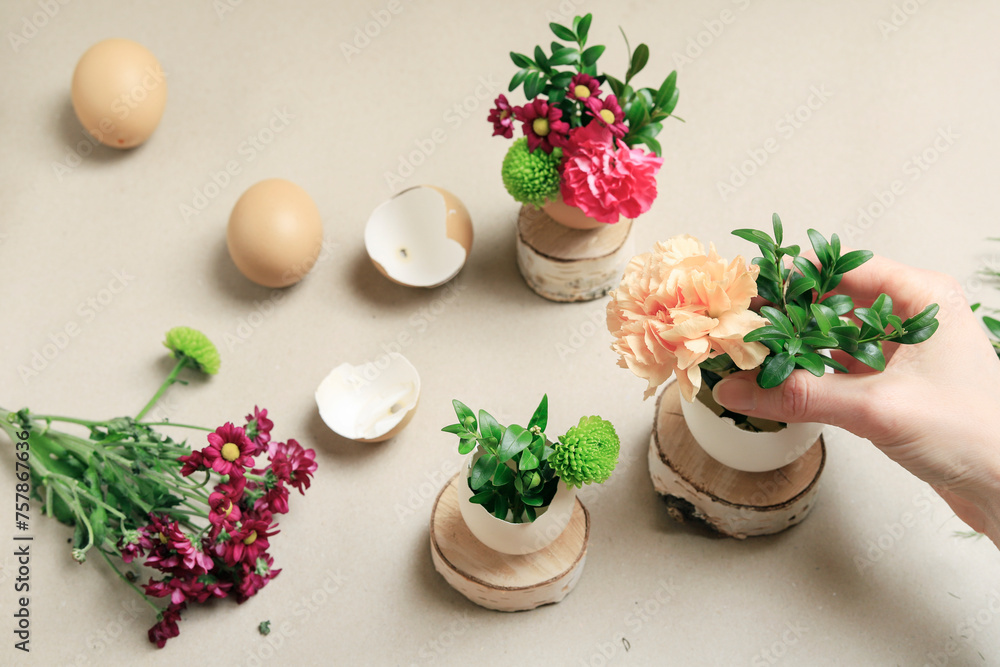Florist at work: woman shows how to make simple Easter decoration with egg shell and various flowers. Florist at work: woman shows how to make simple Easter decoration with egg shell and various flowers.