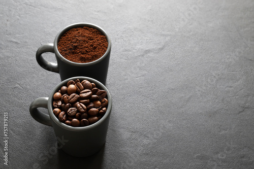 Due tazze di caffè grigie con chicchi di caffè e caffè macinato isolati su sfondo grigio. Vista dall'alto. Copia spazio. photo