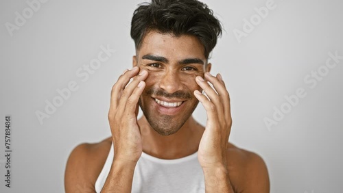 Handsome young hispanic man with beard smiling and stretching facial skin against isolated white background photo