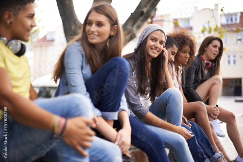 Happy, portrait and girl with students in city for bonding, talking and sitting together. Smile, diversity and young female teenager with group of gen z friends in conversation in urban town.