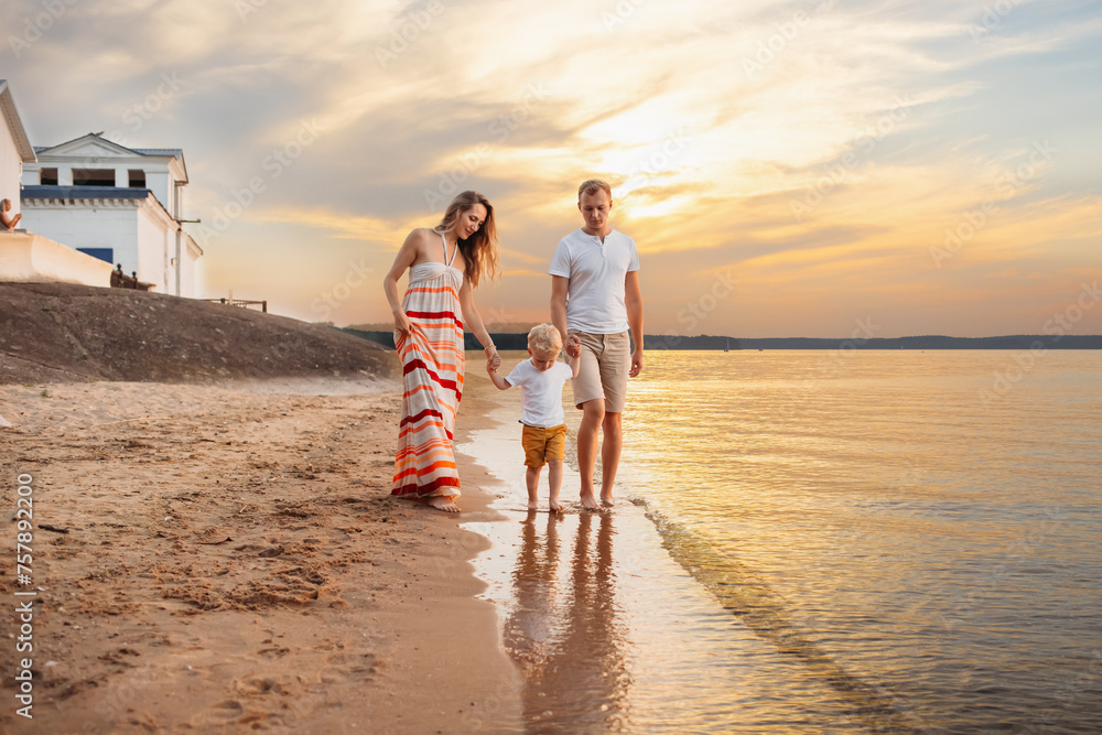 a young family walks on the seashore. parents play with their son on the seashore. vacation