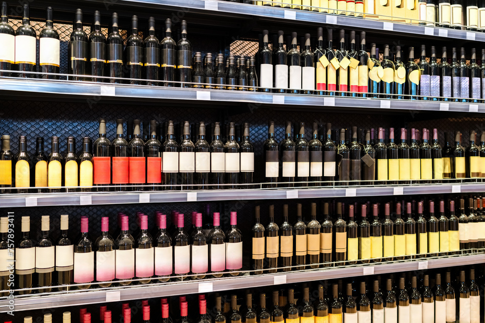 Diagonal view of shelves with variety wine bottles. Liquor store background.
