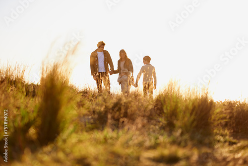 Family  grass and walk at sunset  nature and bonding with exercise for parents and children. Lens flare  autumn and hike on holiday in English countryside  mother and father for outdoor activity